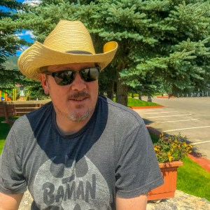 A picture of me enjoying the sun in a straw cowboy hat, sunglasses and Batman T-shirt